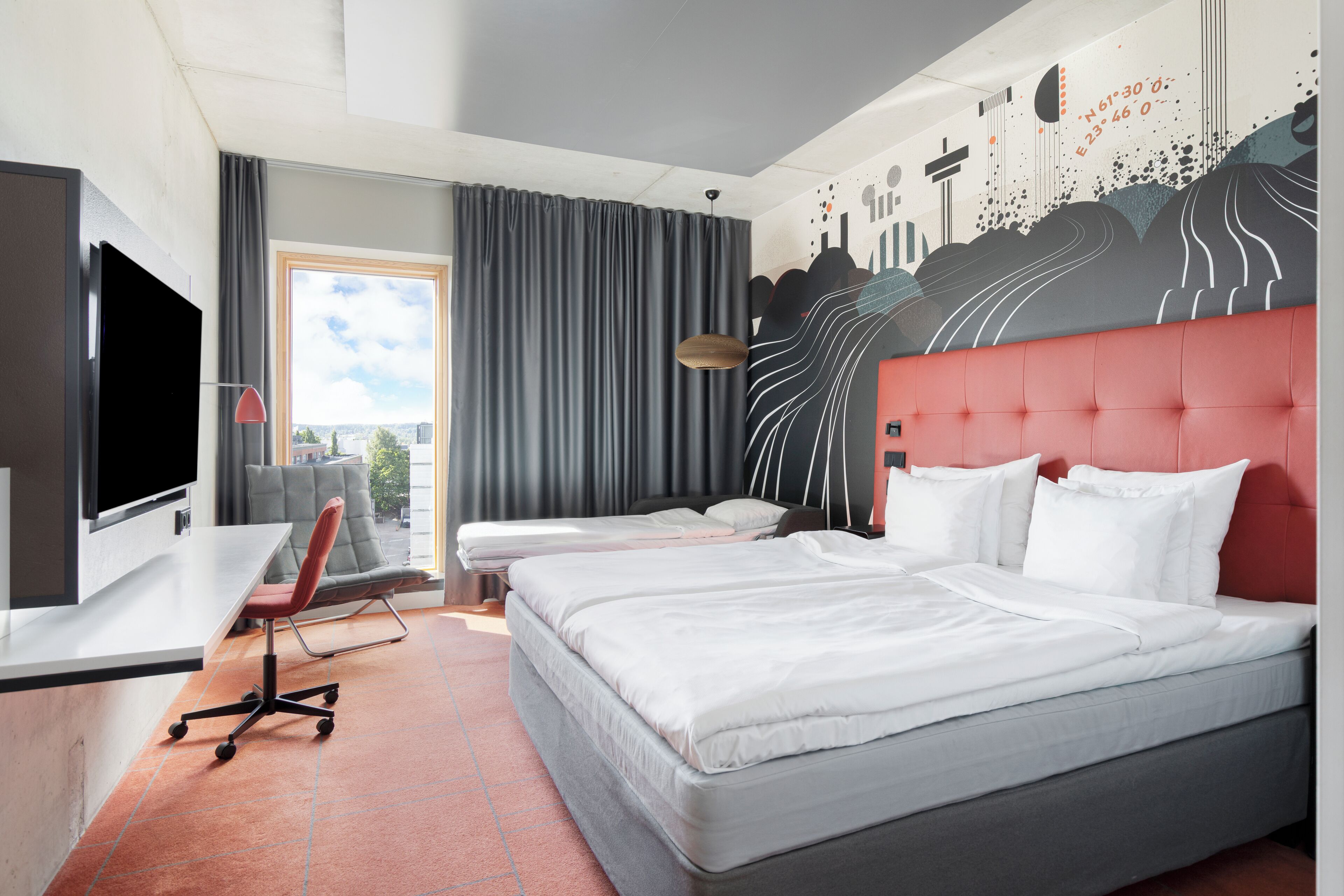 A hotel room with a large bed, a desk with a chair, a TV, and a mural on the wall.