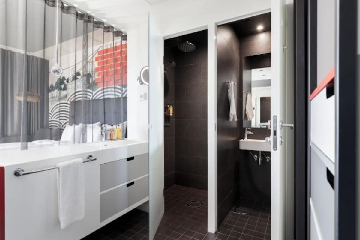 Une salle de bain moderne avec une douche, un meuble-lavabo avec un encadrement en verre et un miroir.