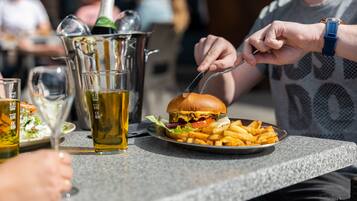 Een eettafel met een bord eten, een glas bier en een fles.