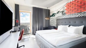 A modern hotel room with a large bed, a desk, a chair, a TV, and a view of the city. - Solo Sokos Hotel Torni Tampere (Tampere)