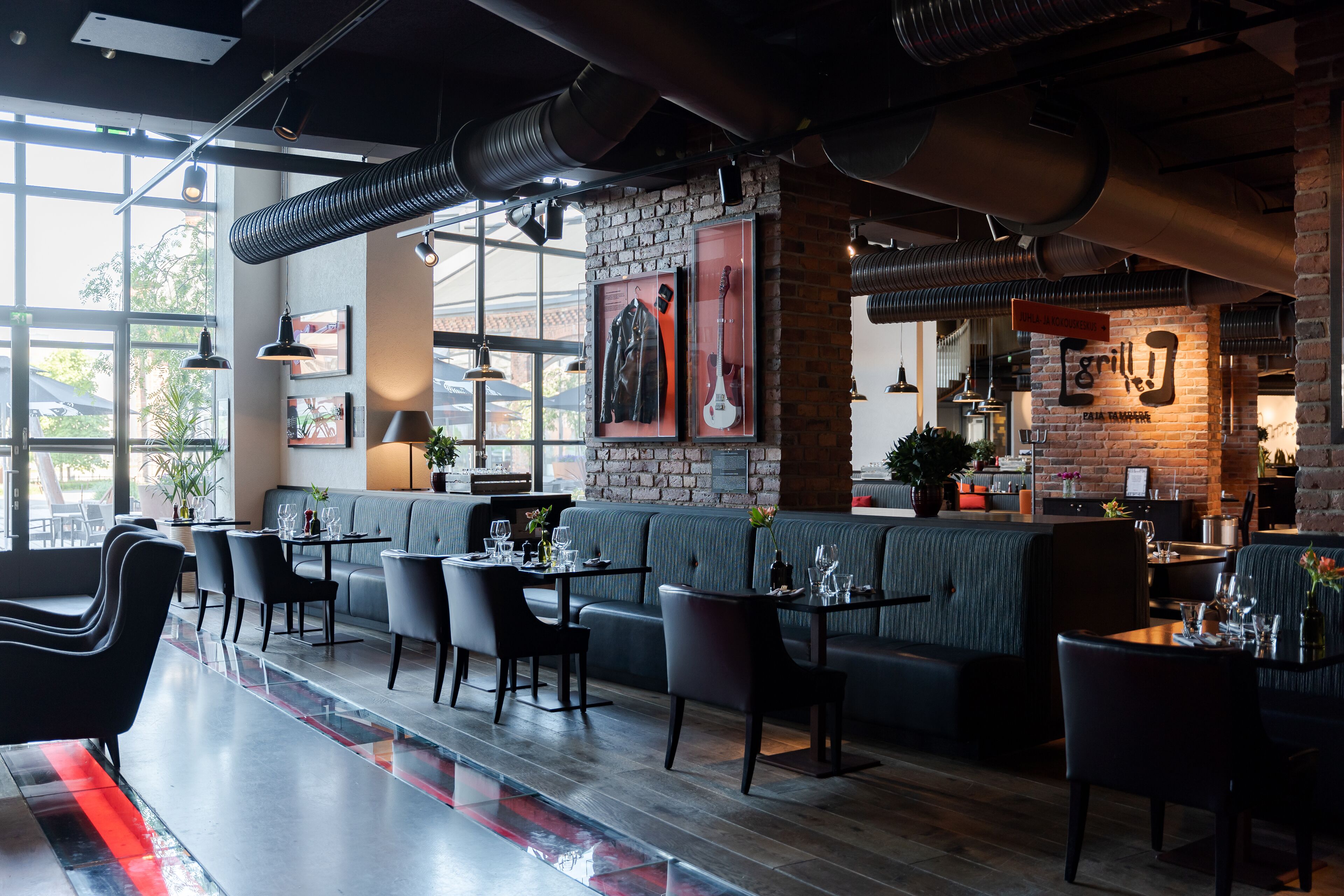 Ein modernes Restaurant mit Ziegelwand, Holztischen und einer Bar.