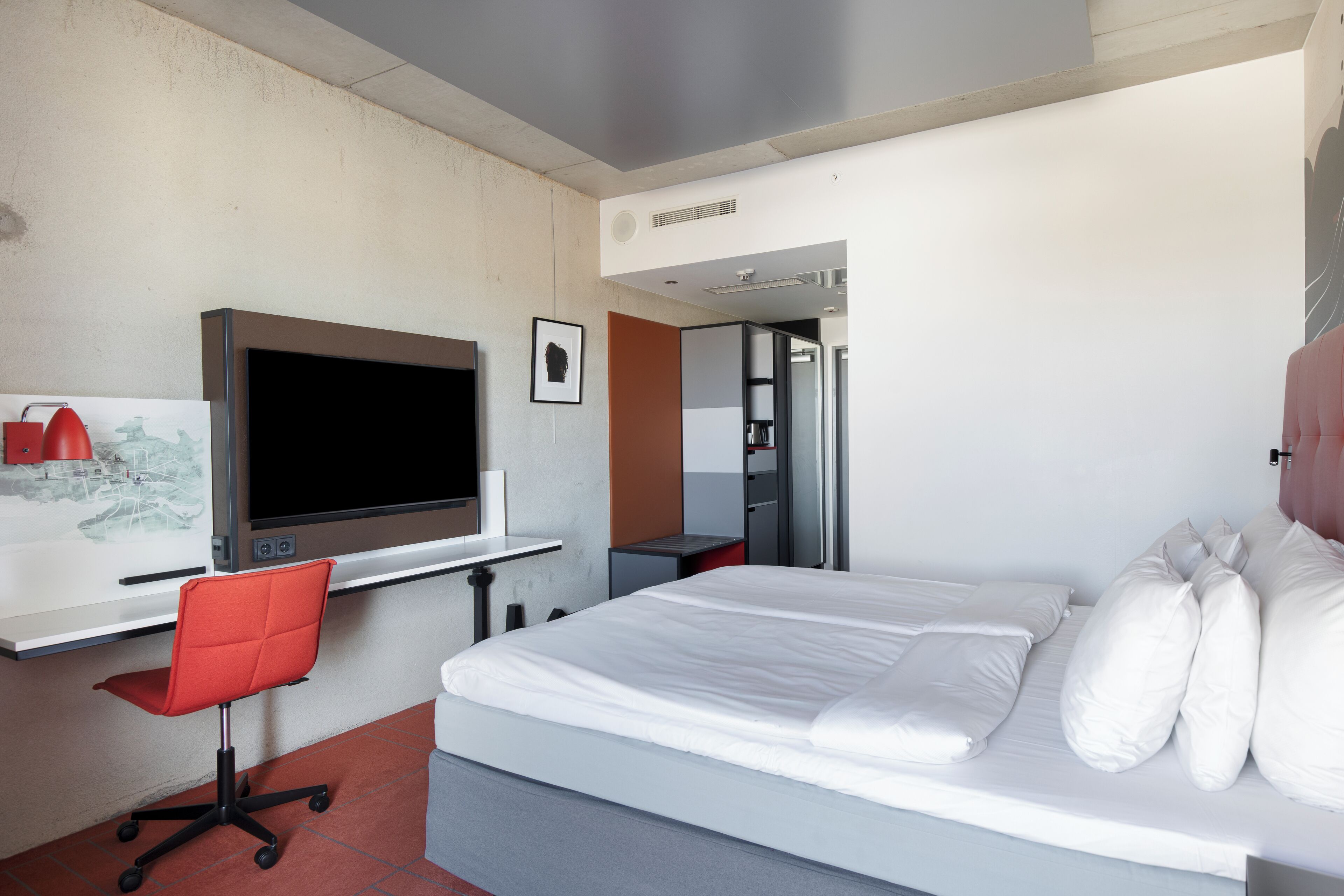 A hotel room with a bed, a desk with a computer, a chair, and a television.