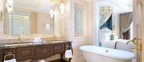 A luxurious bathroom with a marble vanity, a freestanding bathtub, and a large mirror.