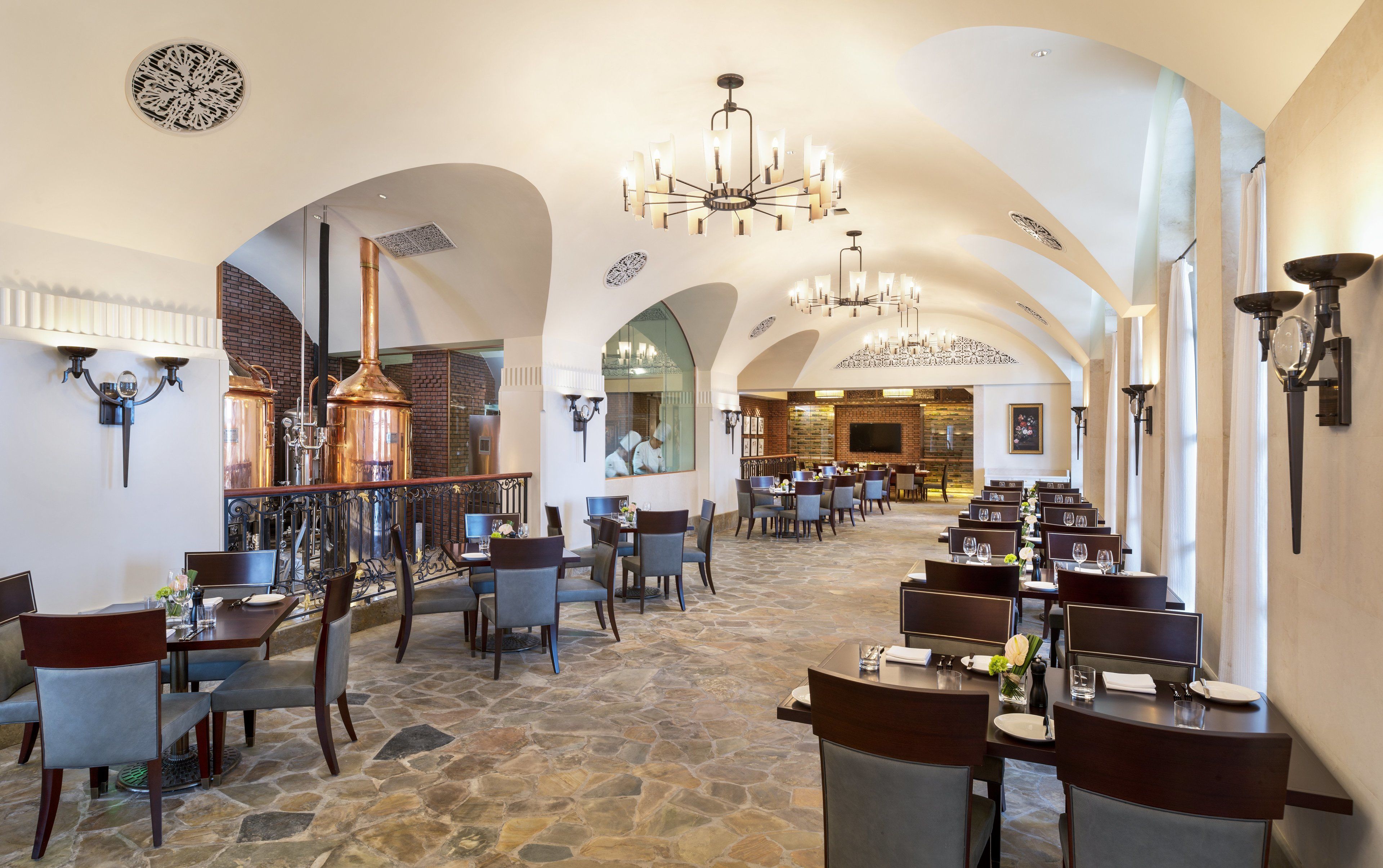 En rummelig restaurant med hvælvede lofter, stengulv og moderne lysarmaturer.