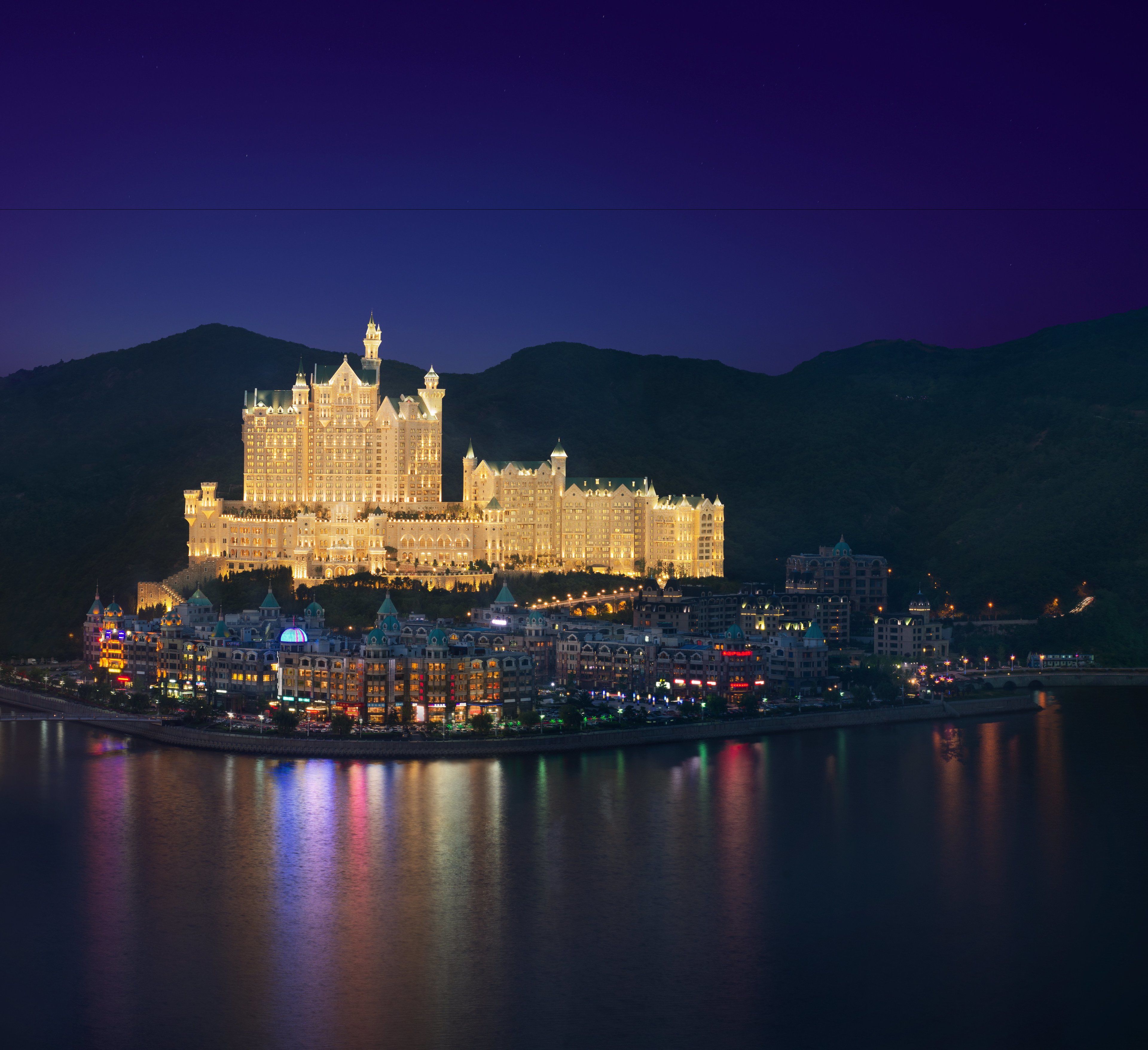 A large, illuminated castle-like hotel with multiple towers and a waterfront view.