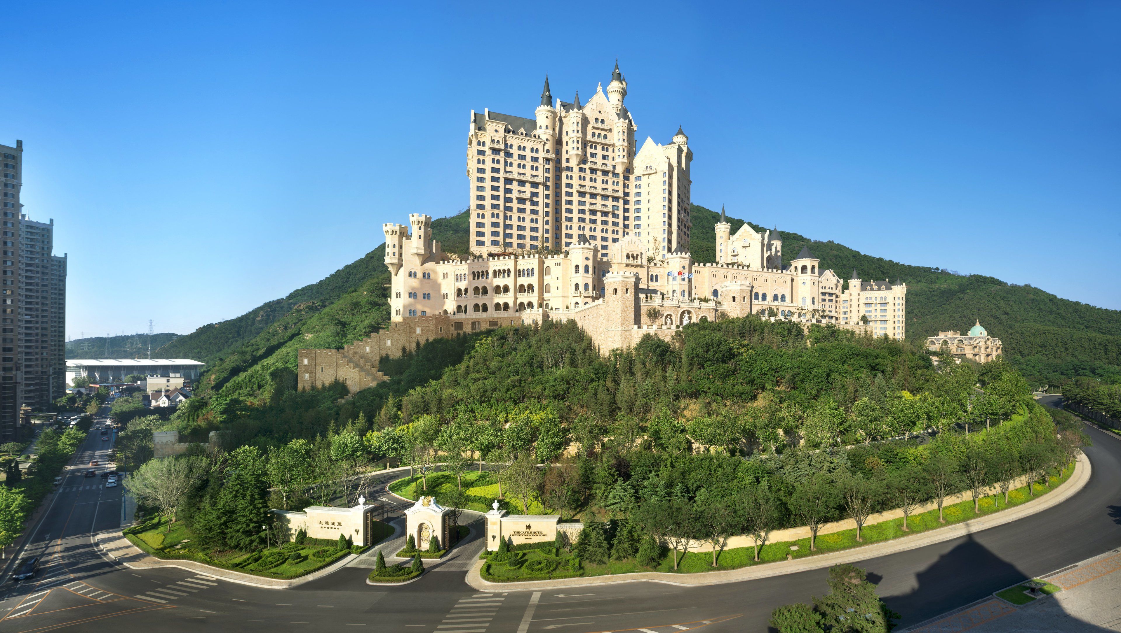 Un gran hotel con aspecto de castillo, con varias torres y una colina verde exuberante.