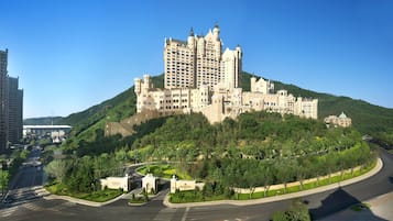 Un gran hotel con aspecto de castillo, con varias torres y una colina verde exuberante.