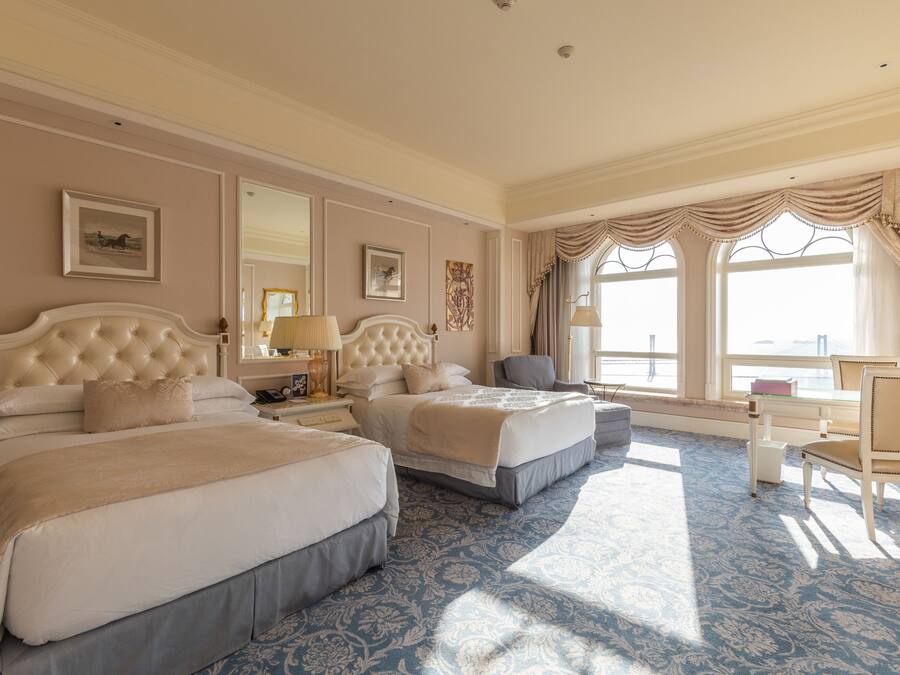 Habitación de hotel con dos camas, un escritorio y una silla.