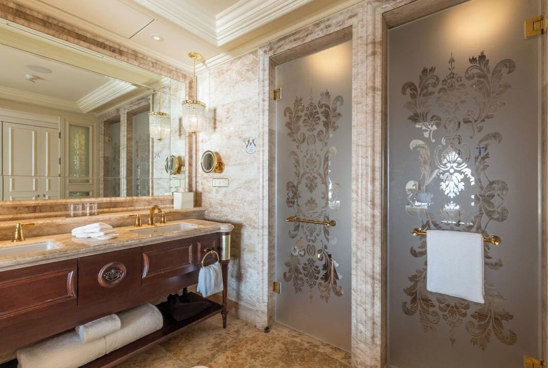 Un baño lujoso con tocador de mármol, lavamanos dobles y un espejo grande.
