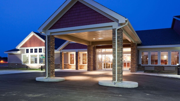 A building with a covered entrance, stone pillars, and a brick facade. - AmericInn by Wyndham Hawley (Hawley)