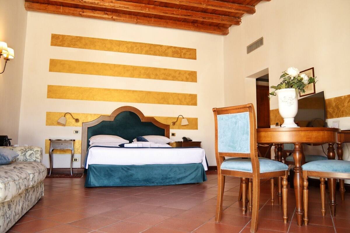 A hotel room with a bed, a chair, a table, and a lamp.