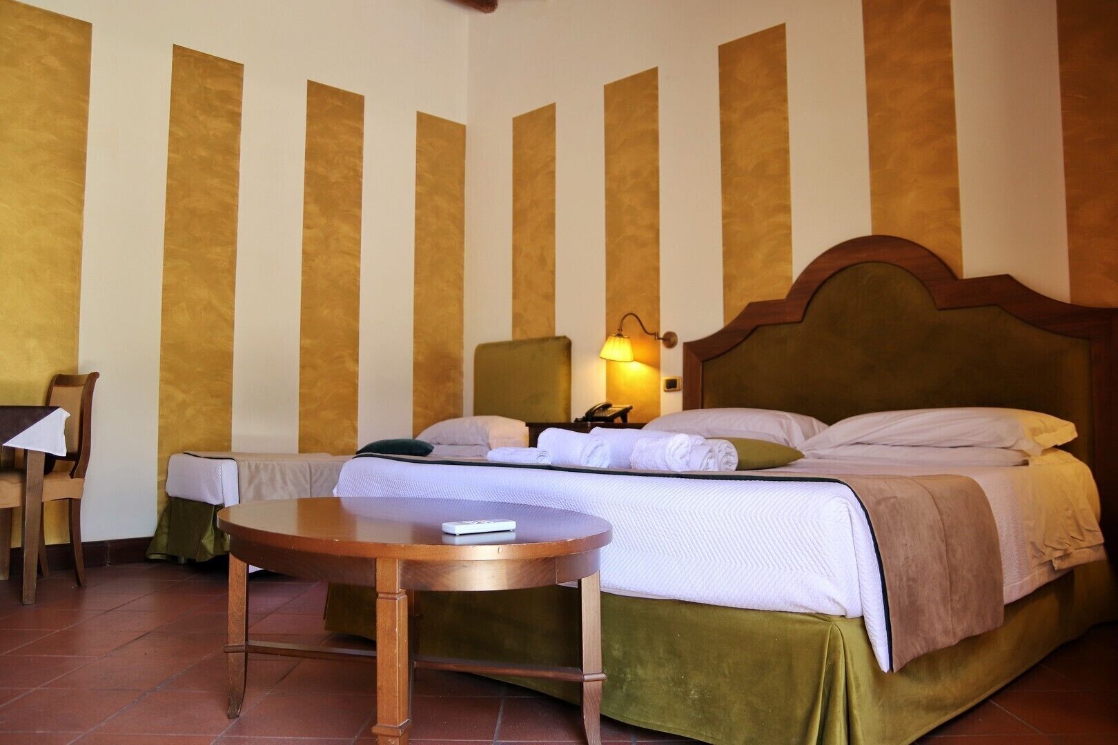 Ein Hotelzimmer mit Bett, Nachttisch, Lampe und einem Sessel.