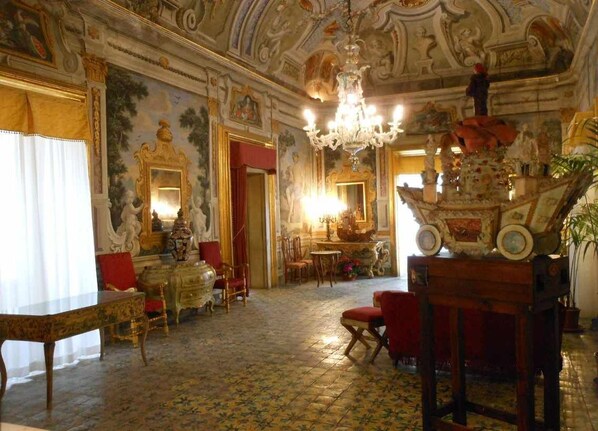 Una sala amplia con decoraciones elaboradas, un candelabro y un espejo grande.