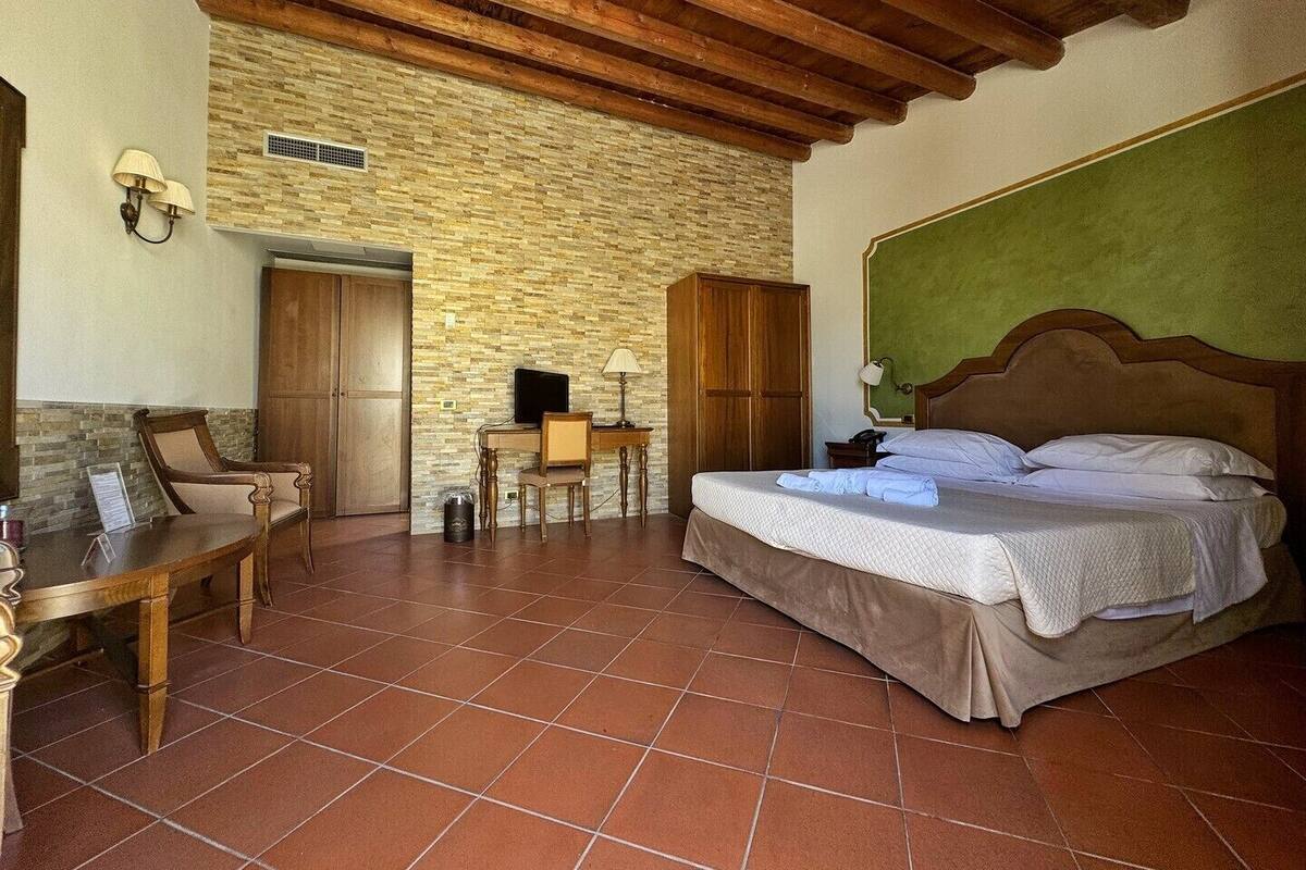A room with a bed, wooden furniture, a stone wall, and a tiled floor.