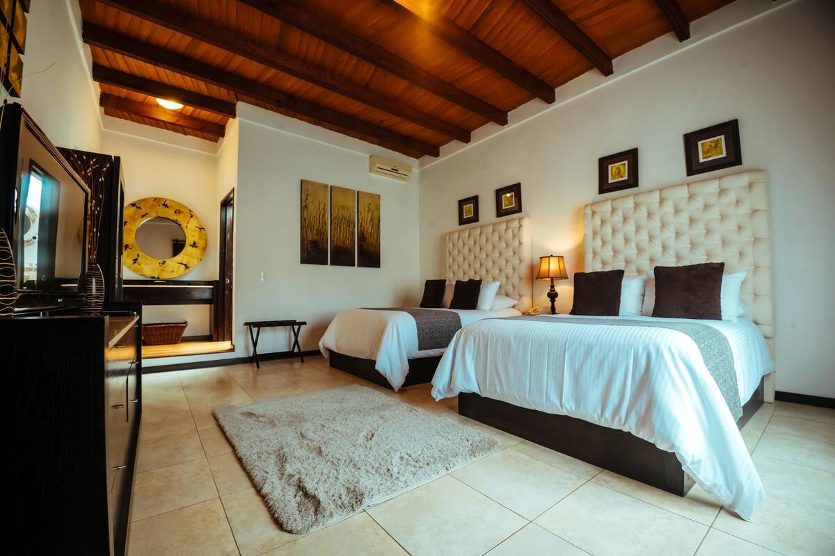 Un dormitorio con dos camas, techo de madera y obras de arte en las paredes.