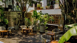 An outdoor patio with wooden flooring, potted plants, and seating areas. - Hotel Boutique Hacienda Guadalupe (San Miguel de Allende)