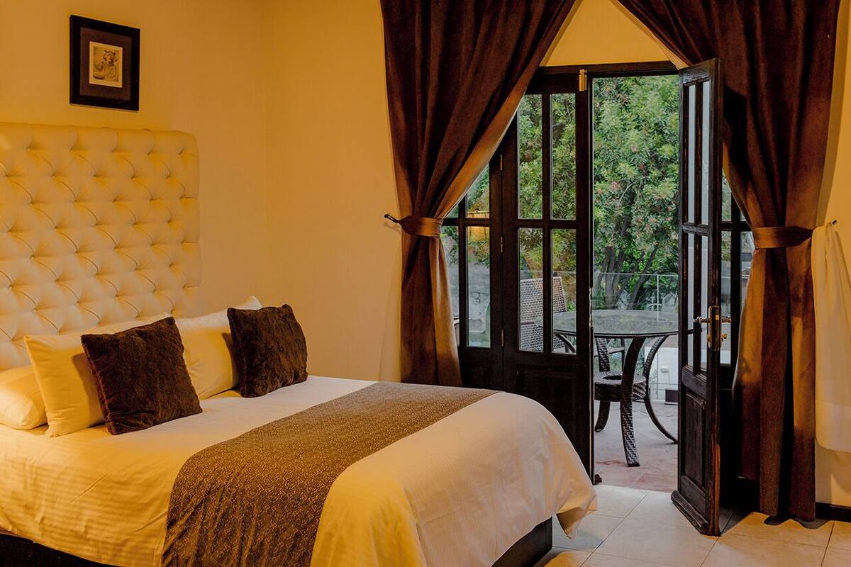Un dormitorio con una cama grande, una ventana con cortinas y vistas al exterior.