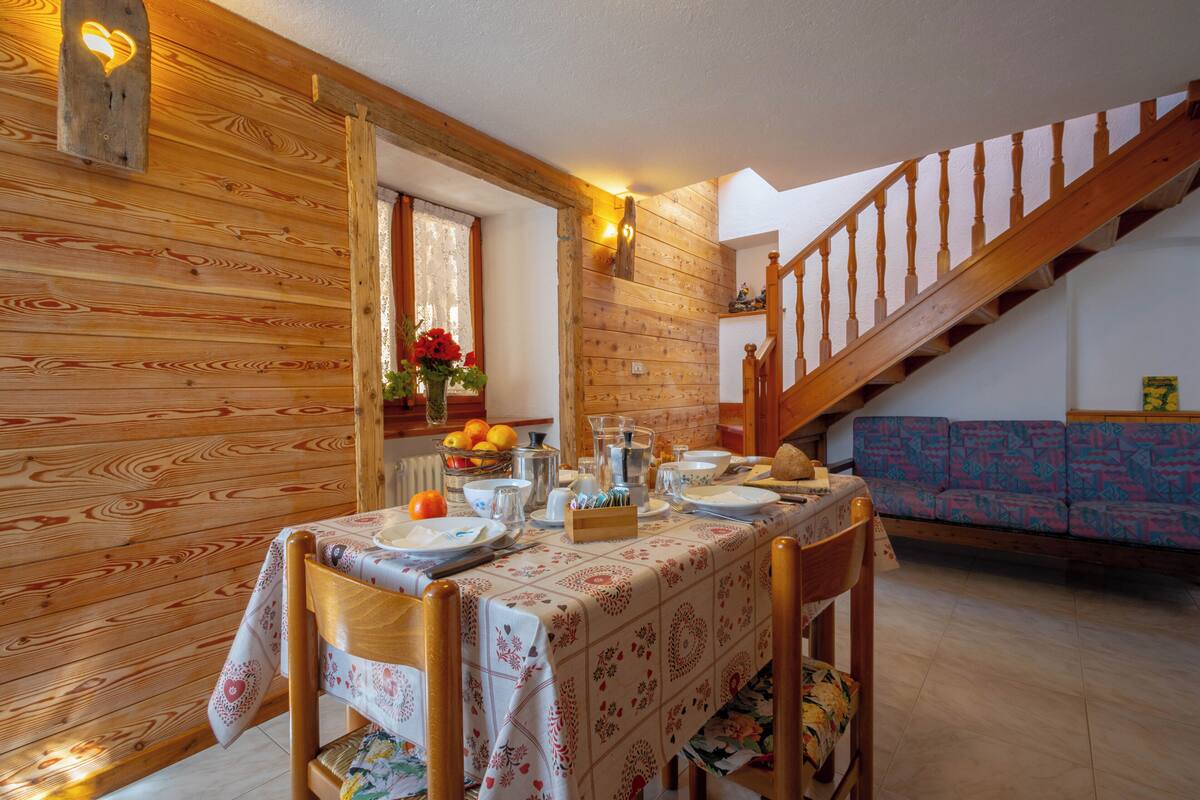 A dining area with a wooden interior, a staircase, and a sofa.