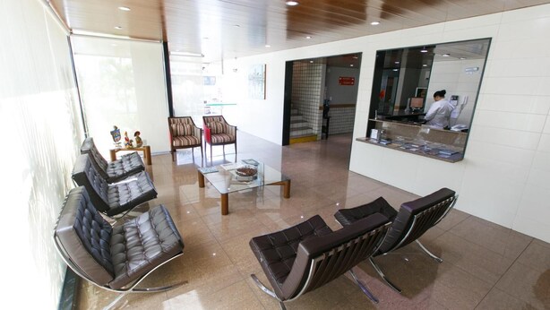A reception area with leather seating, a glass table, and a reception desk with a computer monitor. - Inter Hotel (Recife)