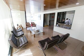 A reception area with leather seating, a glass table, and a reception desk with a computer monitor.