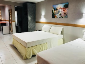 A hotel room with a bed, a desk, and a painting on the wall.