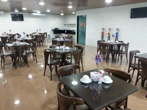 A dining area with multiple tables and chairs, some with floral centerpieces.