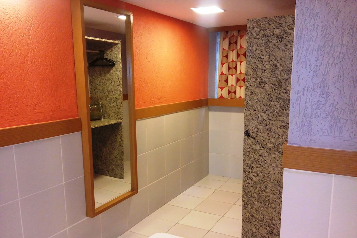 A bathroom with a mirror, tiled walls, a shower area, and a sink.