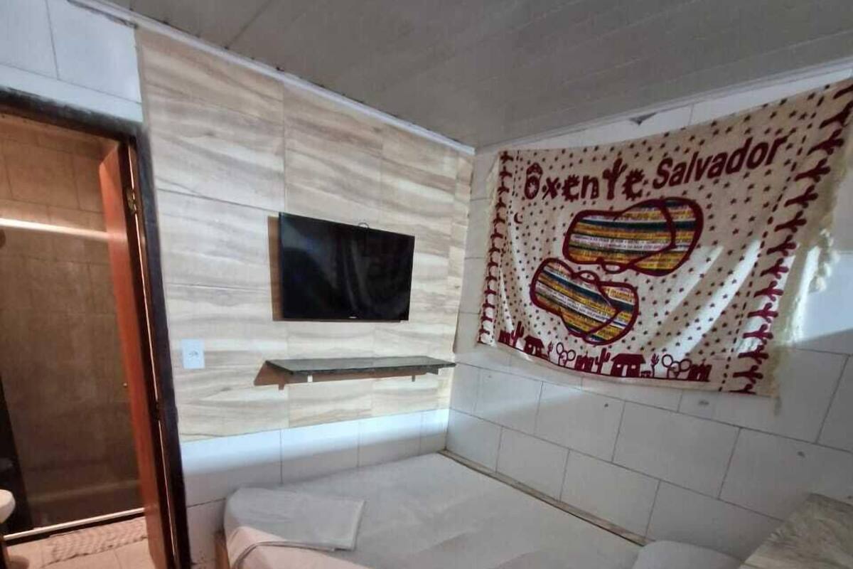 Ein modernes Badezimmer mit einer großen Badewanne, einer Holzbank und einem an der Wand montierten Fernseher.