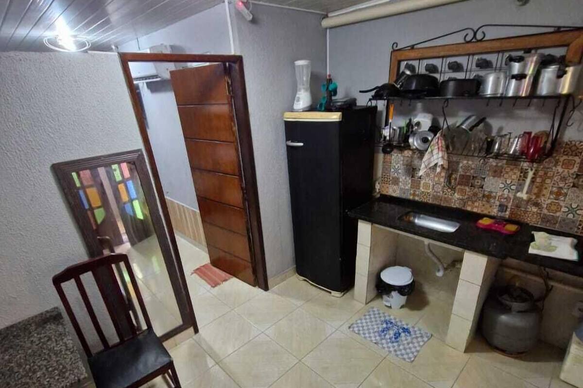 Eine kleine Küche mit Kühlschrank, Spüle und Fliesenboden.