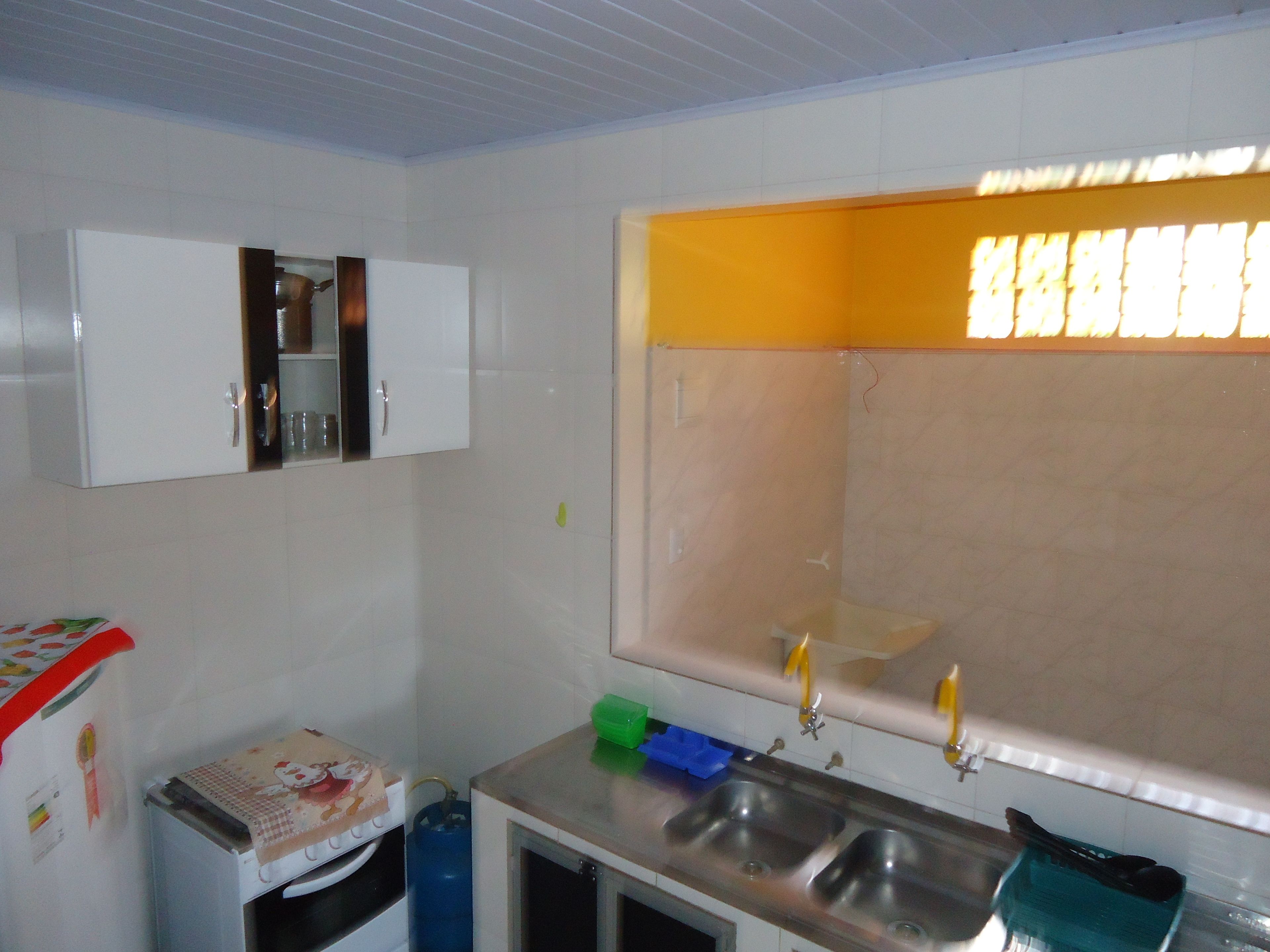 A small kitchen with white cabinets, a sink, and a window with yellow blinds.