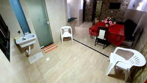 Een kamer met een badkamer, een eethoek met een rode tafelkleed en een bank.