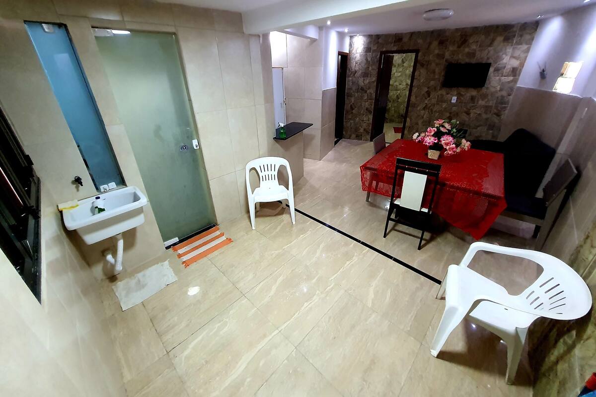 Ein Zimmer mit Bad, einem Essbereich mit roter Tischdecke und einem Sofa.