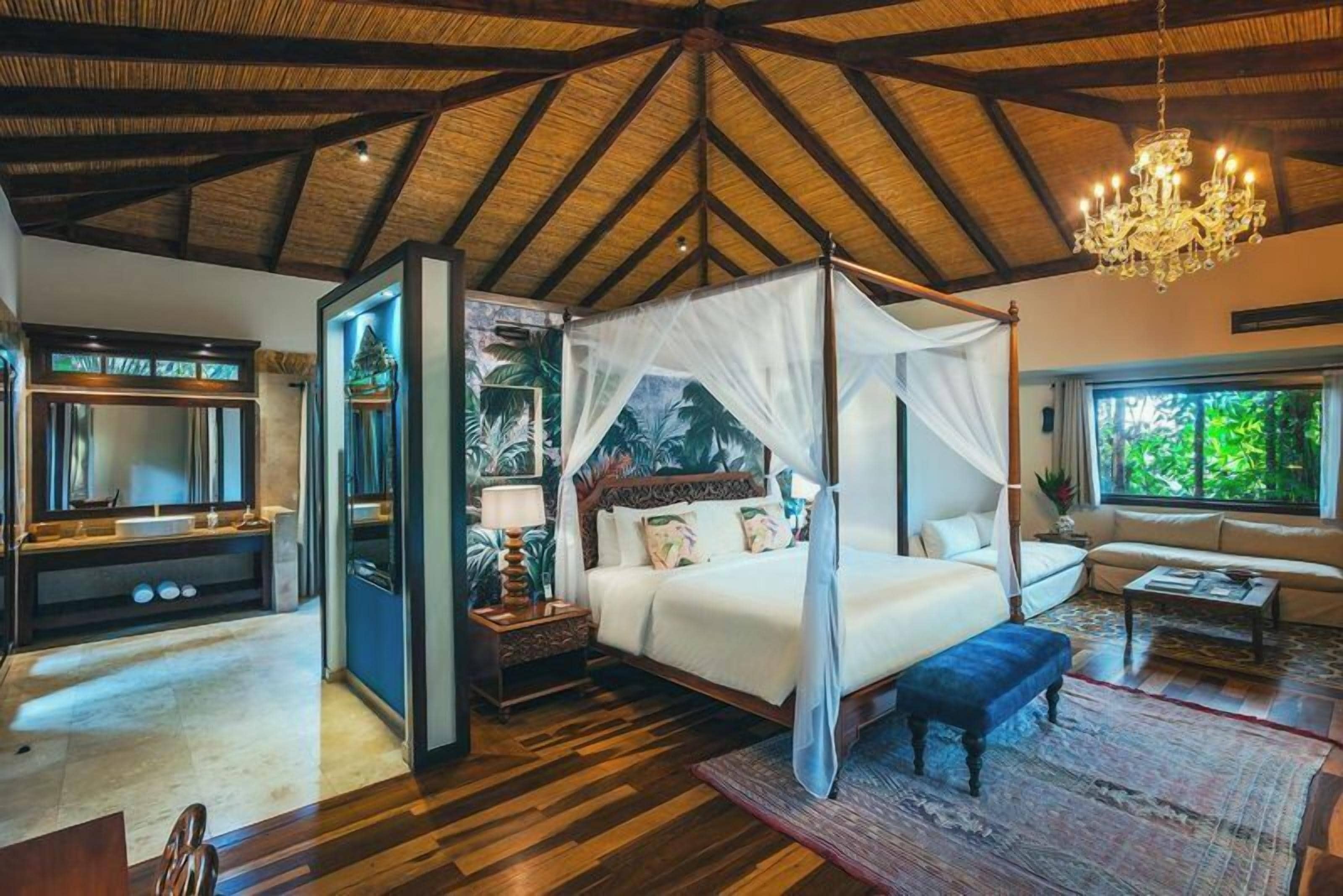 A spacious bedroom with a four-poster bed, a large window, and a chandelier.