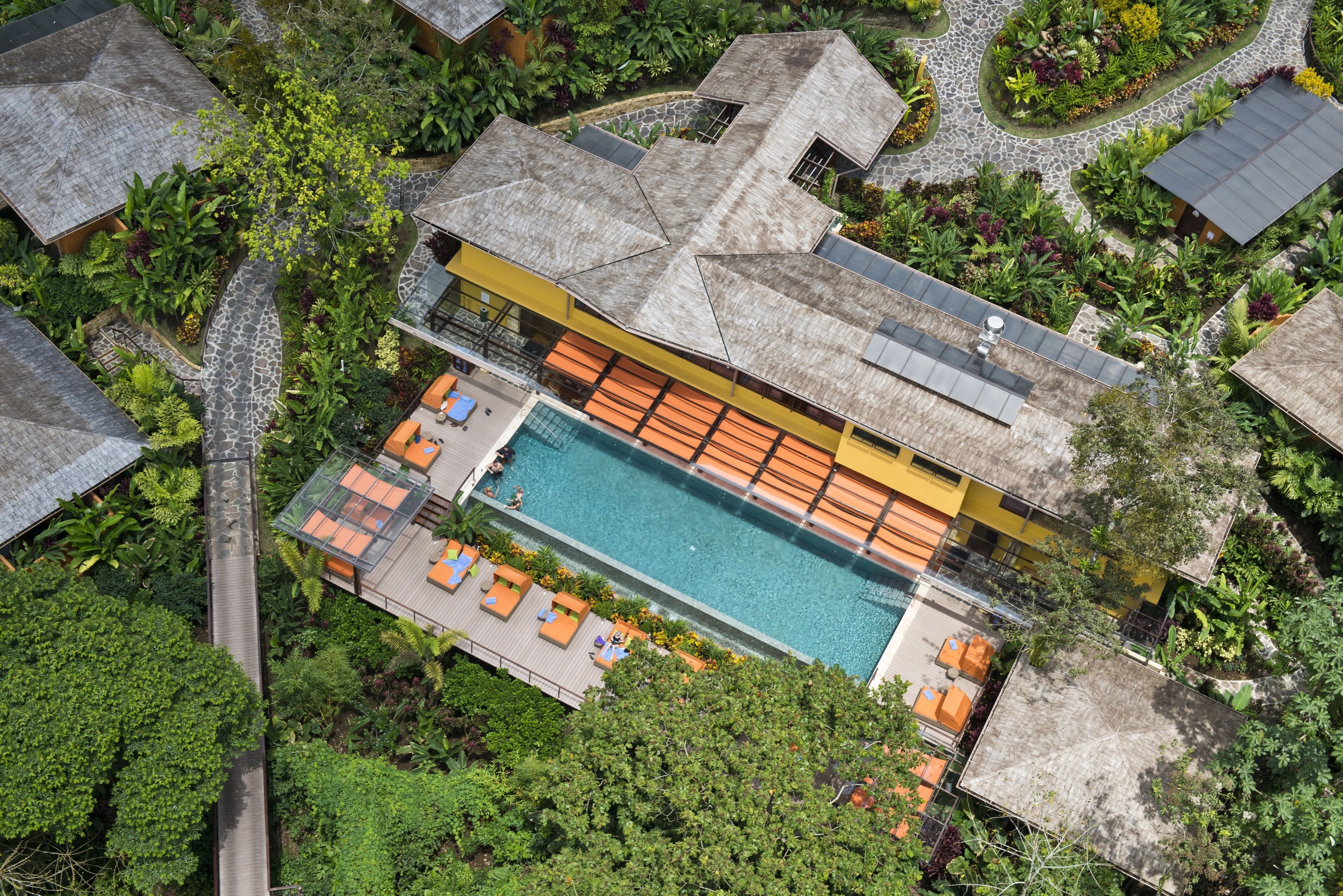A resort with a swimming pool, multiple rooms, and lush greenery.