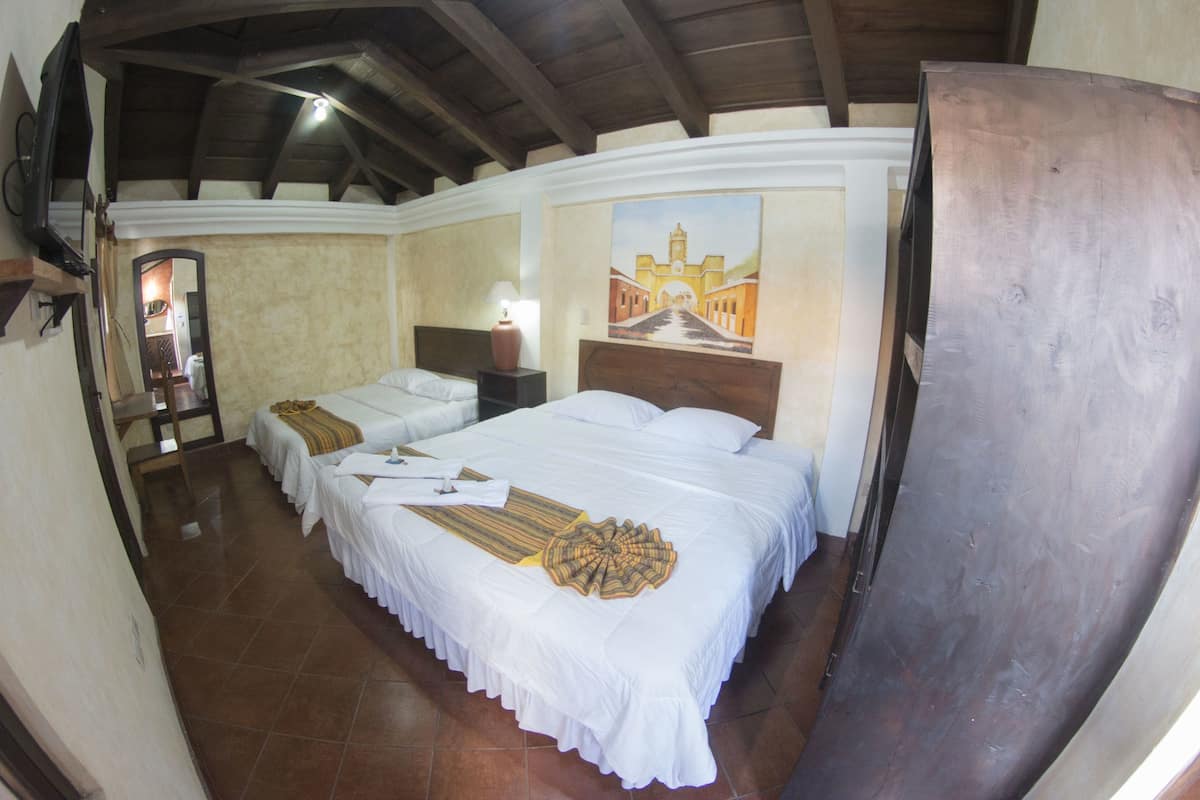 Une chambre avec deux lits, un tableau au mur et un plafond en bois.