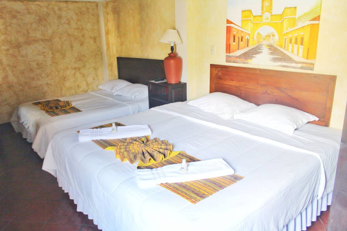 Une chambre d’hôtel avec deux lits, une table de chevet avec une lampe et un tableau au mur.