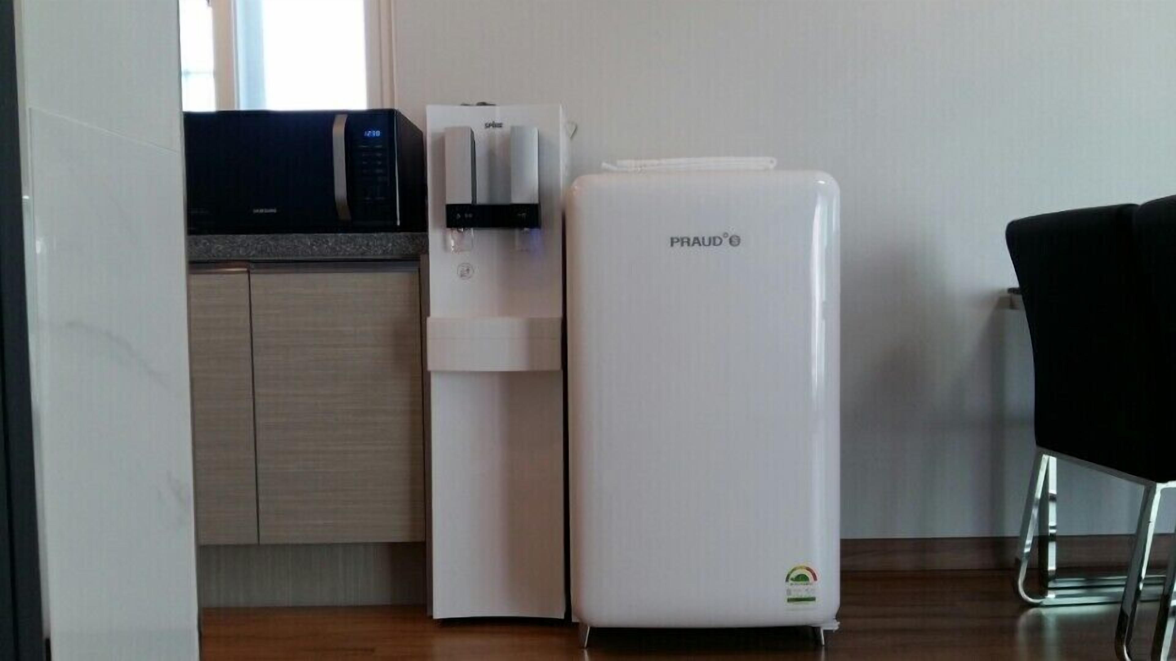 Una cocina compacta con microondas, dispensador de agua y refrigerador.