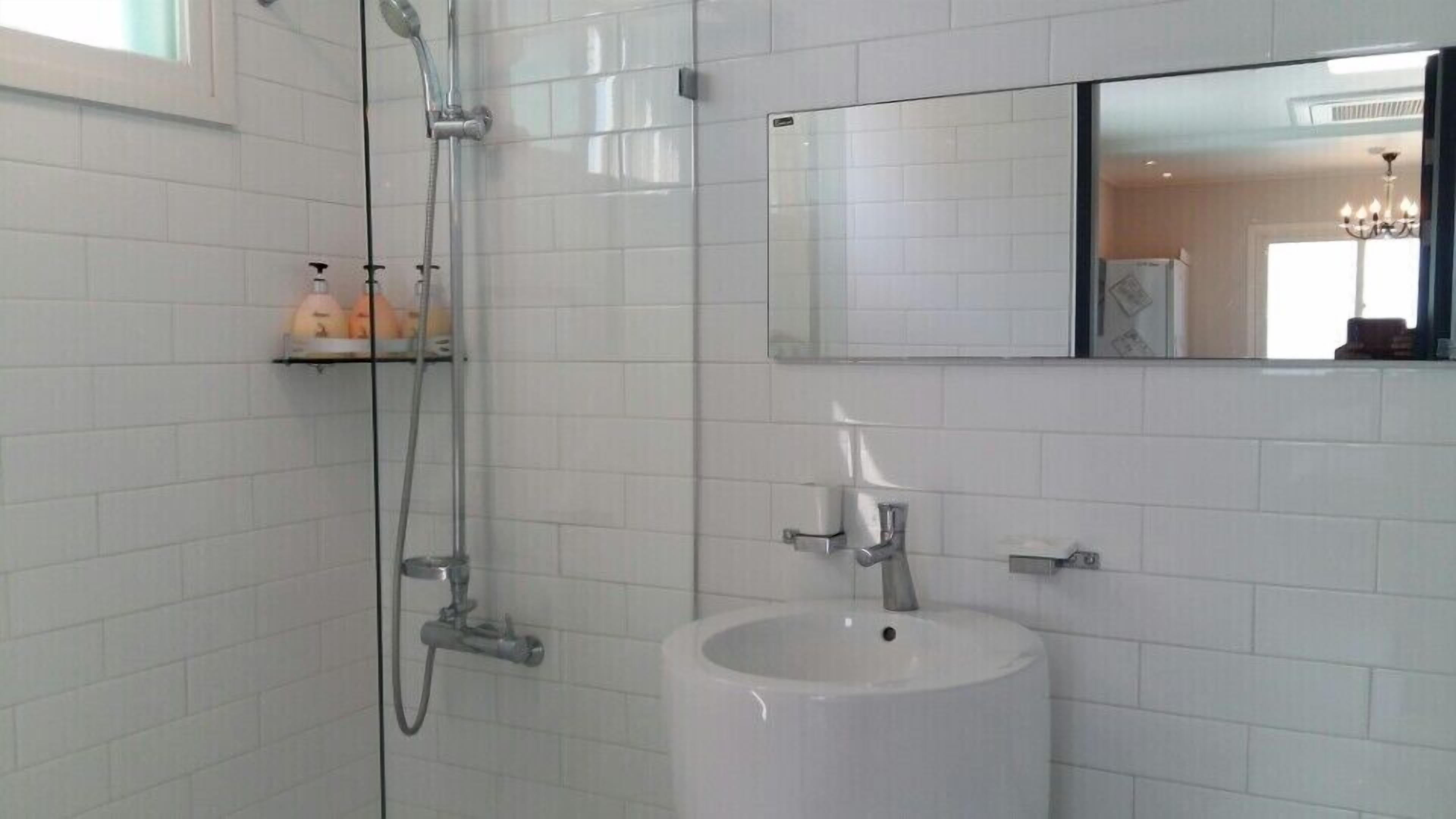A bathroom with a white sink, a mirror, and a shower.