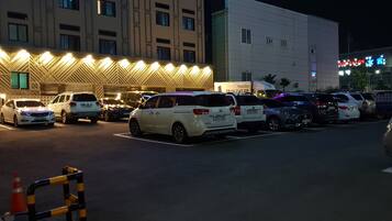 Un parcheggio con diverse auto parcheggiate di fronte a un edificio con insegne illuminate.