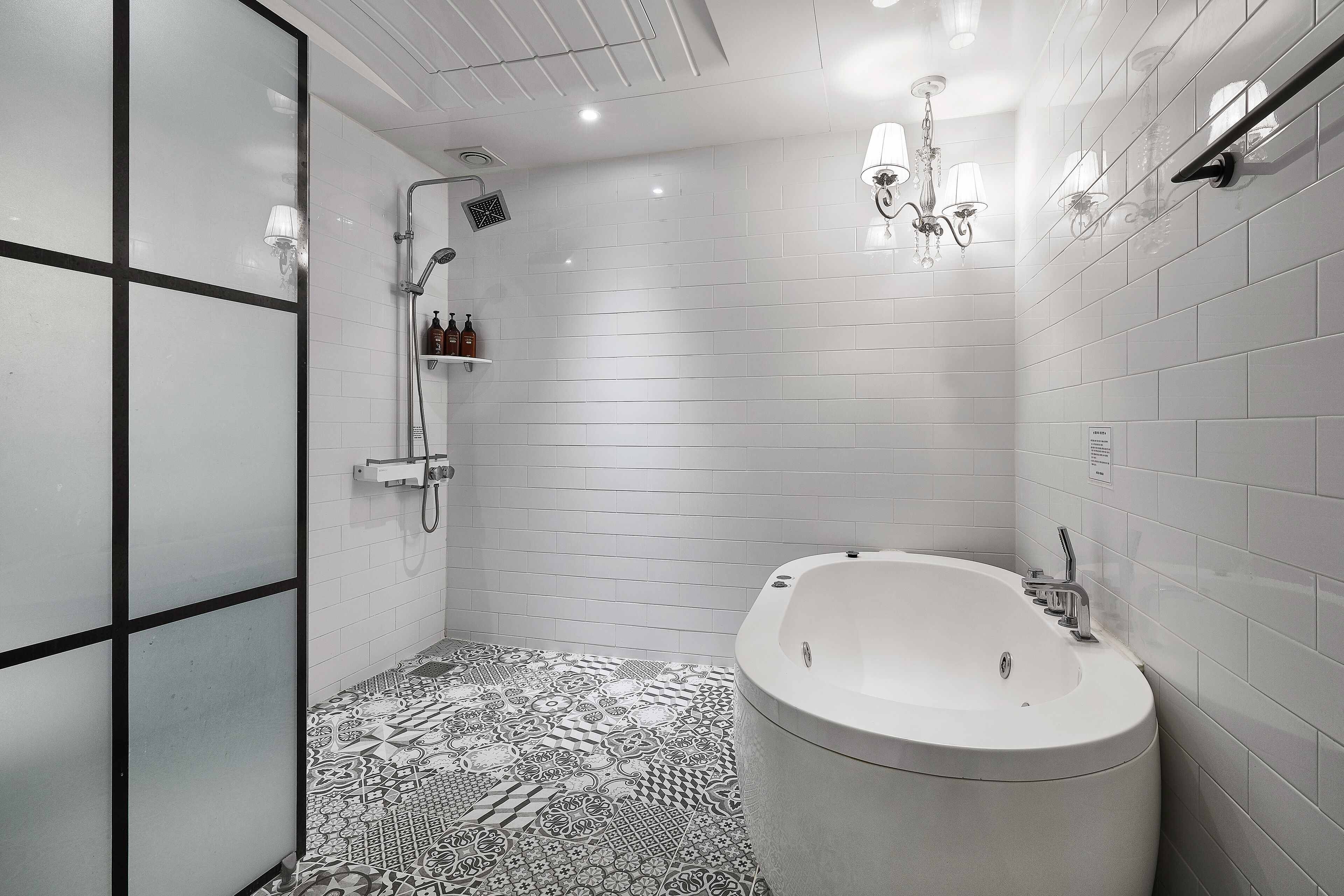 A modern bathroom with a freestanding bathtub, a shower area, and patterned floor tiles.
