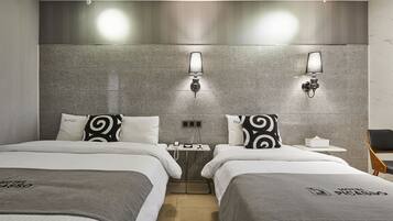 A hotel room with two beds, a nightstand, and a chair.