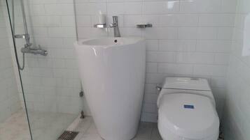 Un baño con un lavamanos blanco pedestal, un inodoro y una cabina de ducha de vidrio.
