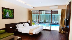 A hotel room with a bed, a glass door leading to a pool area, a TV, and a painting on the wall. - Devata Suite & Residence (Legian)
