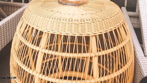 A restaurant interior with white wicker furniture, a central woven table, and a Christmas tree in the background. - Devata Suite & Residence (Legian)