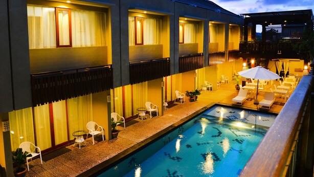 A hotel with a swimming pool, outdoor seating, and a covered patio area. - Devata Suite & Residence (Legian)