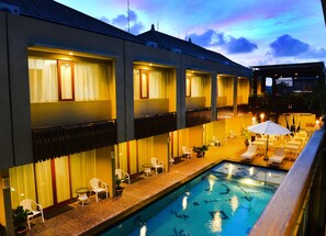 Um hotel com piscina, área de estar externa e um pátio coberto.