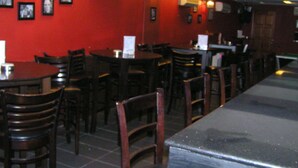A restaurant interior with tables and chairs, red walls, and wall-mounted lights. - Cosmic Boutique (Kuala Lumpur)