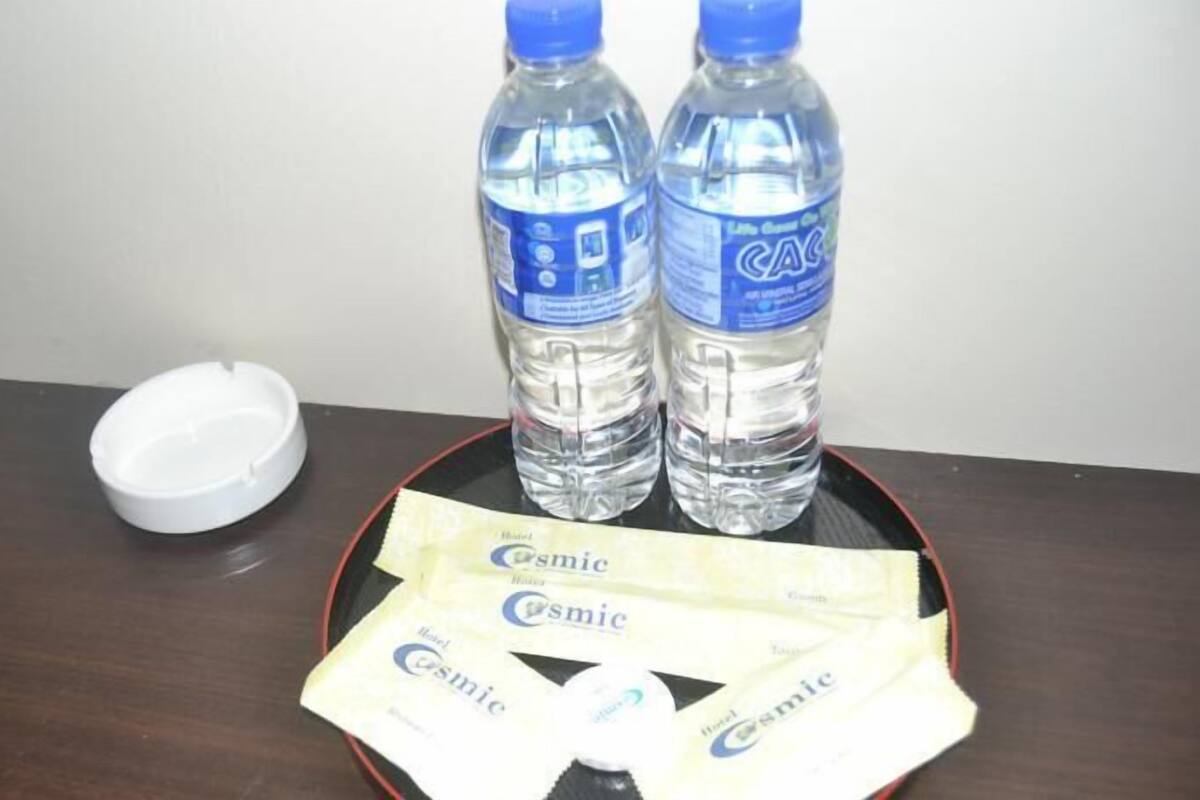 A table with two bottles of water, a white lid, and several packets of hotel amenities.