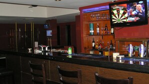 A bar area with a dartboard, shelves with bottles, and a television displaying a sports event. - Cosmic Boutique (Kuala Lumpur)
