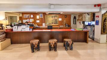 A reception desk with a wooden counter, a clock, and framed artwork on the wall.